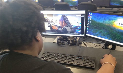 student editing video footage of another student handling video camera
